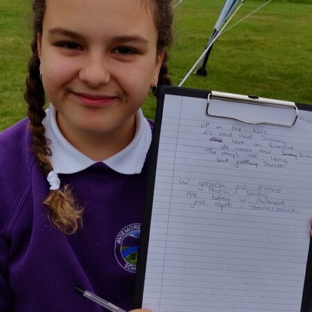 Schoolgirl shows her poem in Polish and English on a clipboard