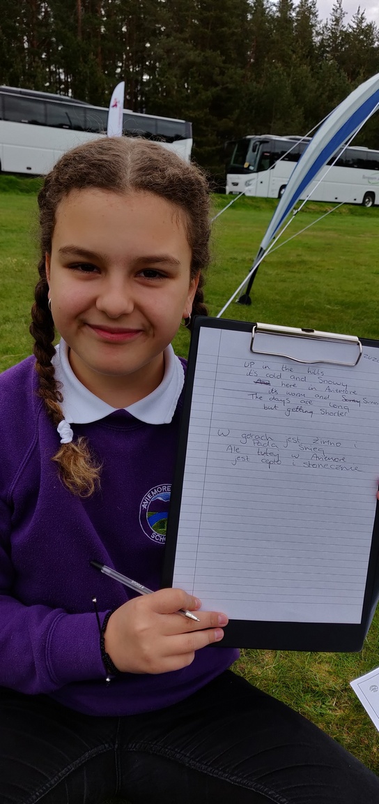 Schoolgirl shows her poem in Polish and English on a clipboard
