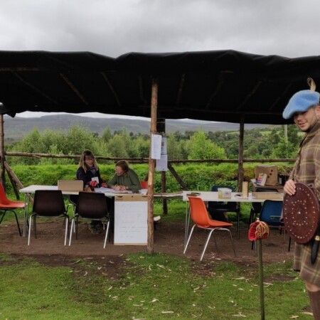 Shelter with tables, Cairngorms National Park sign and man in Highland dress