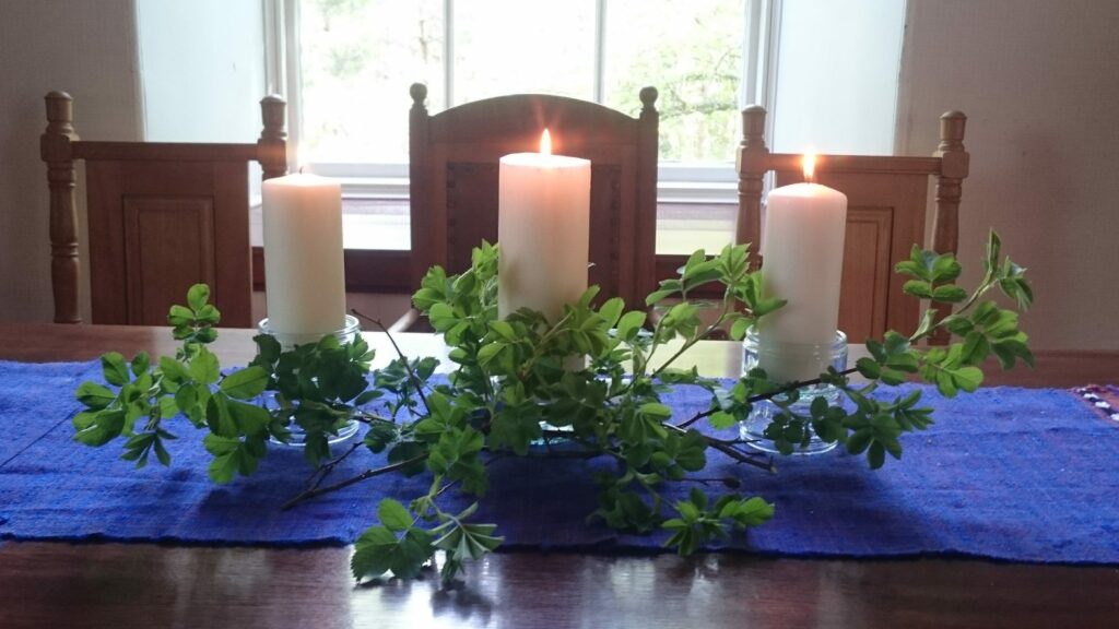 Three candles and greenery on a wooden table
