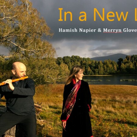 Hamish Napier playing bamboo flute and Merryn Glover beside a Scottish loch in autumn