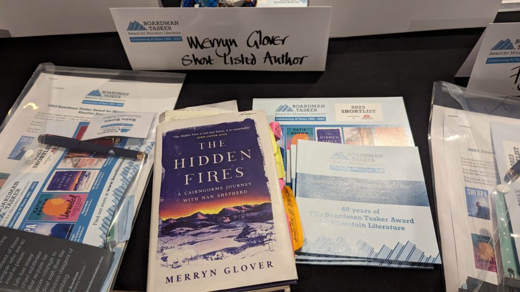 Copy of The Hidden Fires book in front of sign reading 'Merryn Glover shortlisted author'