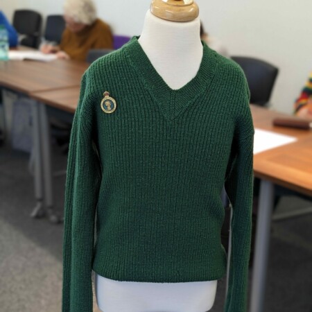 dark green Womens Land Army jumper with badge on a mannequin
